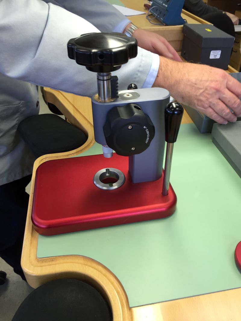 Hands working a case press with a red base on the green bench mat