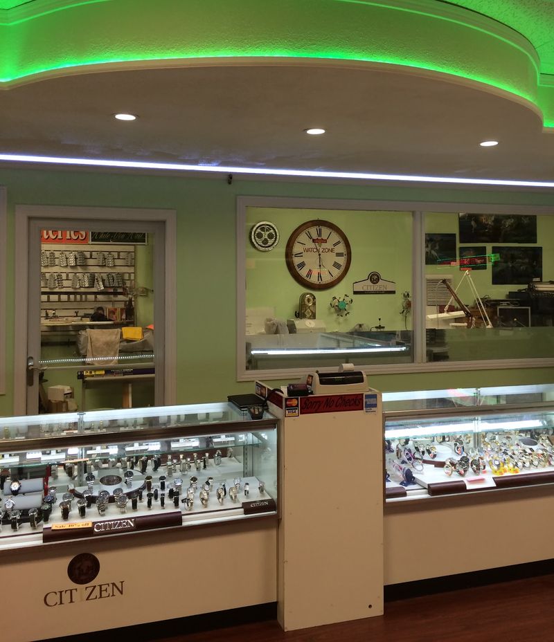 The showroom: glass watch display cases, and a window into the workshop with a Watch Zone wall clock