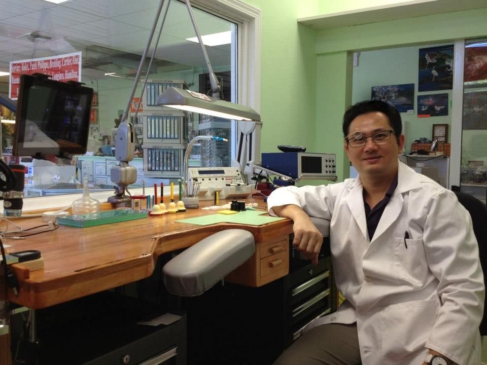 Watch Zone's watchmaker in a white lab coat, seated at his bench in the workshop