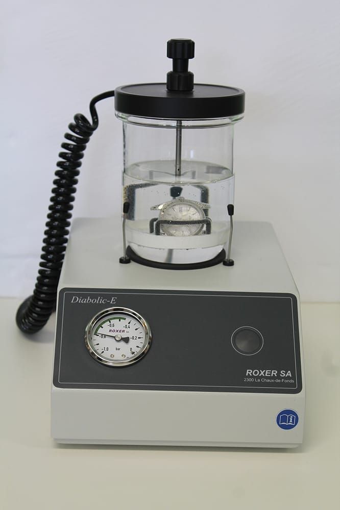 A Roxer Diabolic-E pressure tester with a glass water chamber and gauge